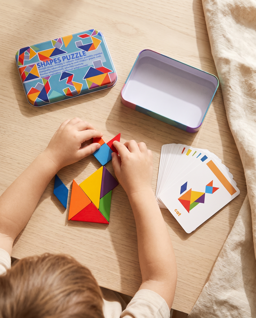 Manos de niño colocando la última pieza del tangram Enigma para completar la silueta de un gato, con la tarjeta de reto al lado