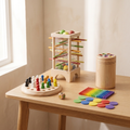 Nooki Play Pack: Lluvia, Bosque y Juncos, los tres juegos de madera del pack, juntos sobre una mesa de roble claro