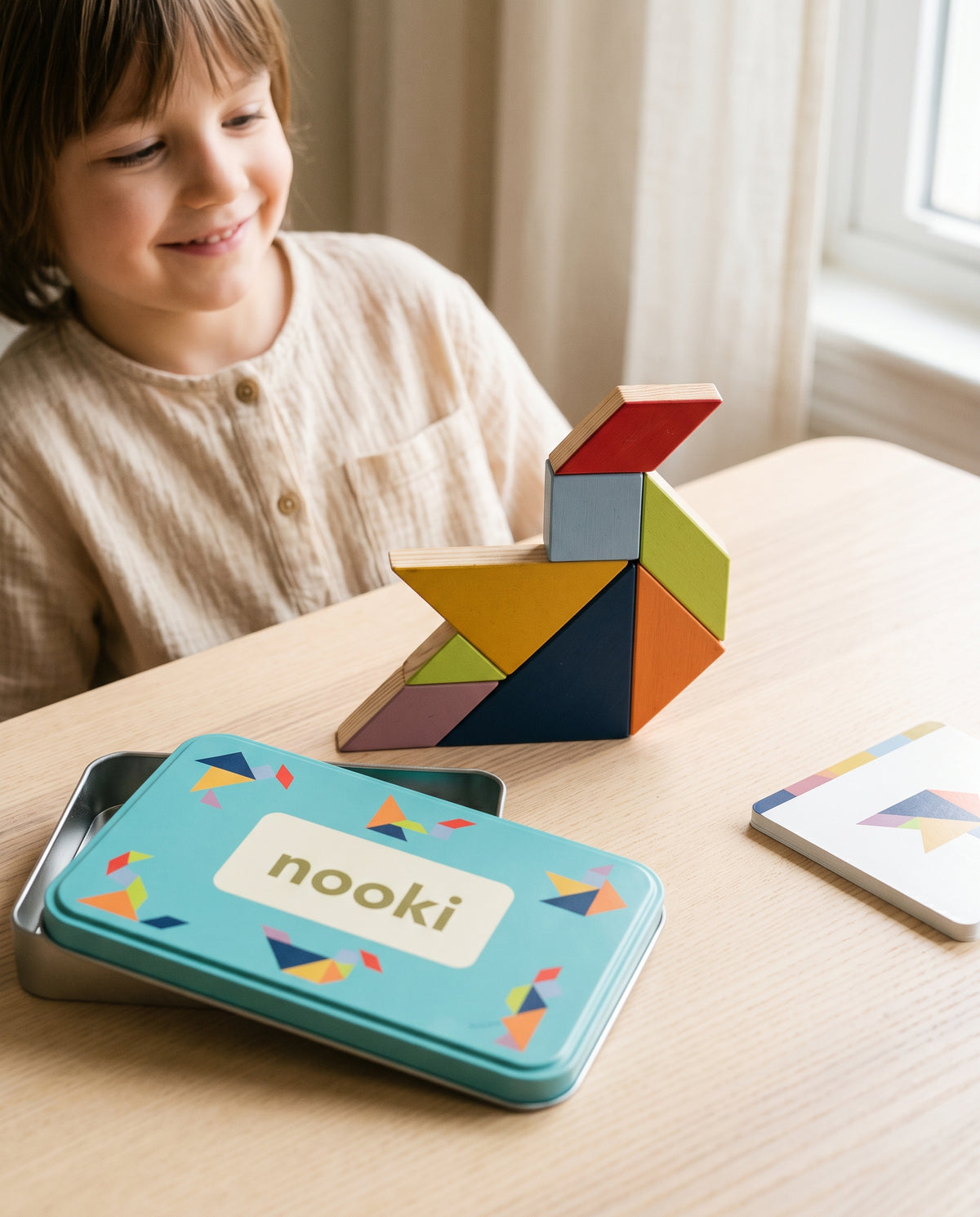 Niño sonriendo tras completar una figura con las siete piezas del tangram Enigma